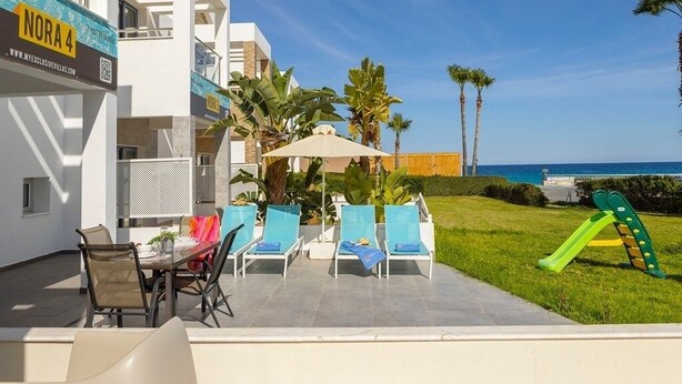 Un bâtiment moderne doté d’un patio comprenant une table, des chaises et une structure de jeux pour enfants.