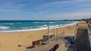 Une plage avec une promenade en bois, une poubelle et un poste de surveillance pour les sauveteurs.