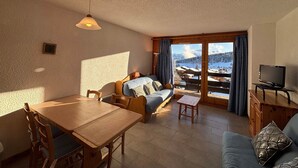 A cozy living room with a sofa, a dining table, and a TV.