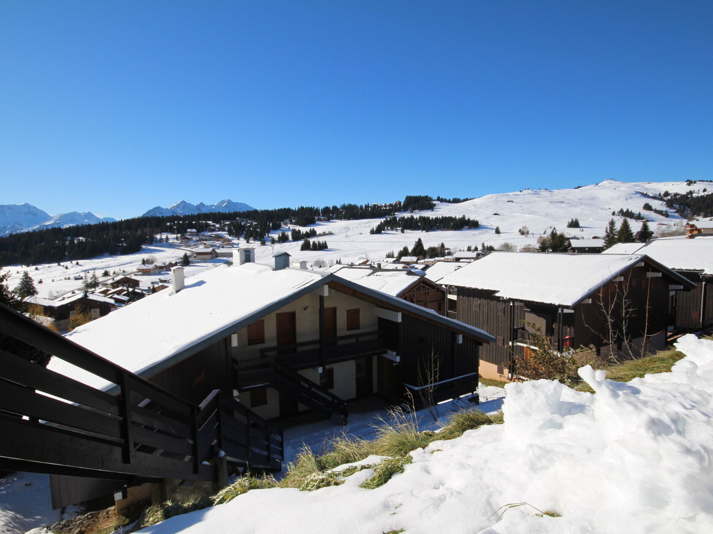 A snow-covered mountain village with wooden buildings and a clear blue sky.