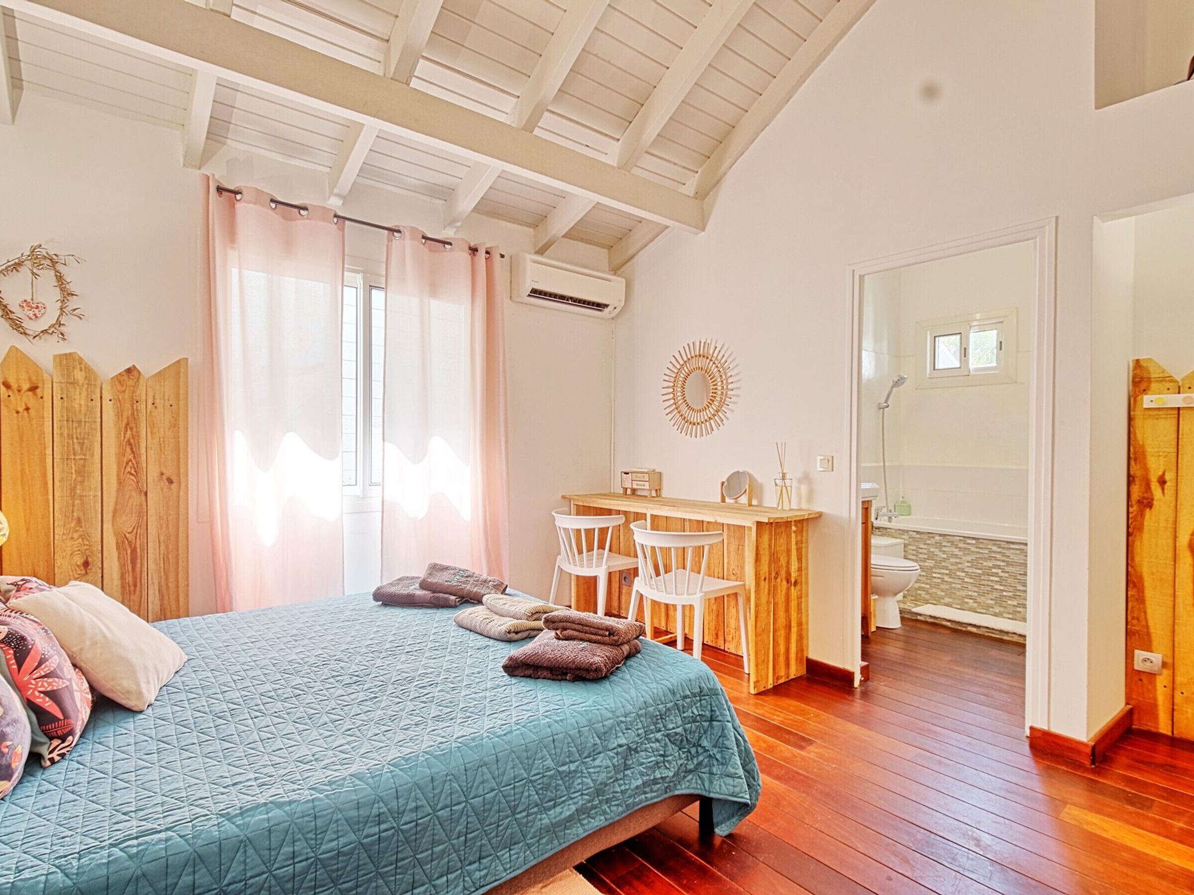 A bedroom with a bed, a wooden desk, and a bathroom.