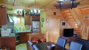 A wooden cabin interior with a kitchen, dining area, and a staircase. - Three charming log cabins in a gated property at the beautiful Troodos mountain (Spilia)