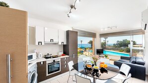Una cocina moderna con vistas a una piscina y un comedor con mesa y sillas.