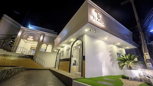 A modern hotel with a prominent 'TIAMO' sign, a staircase leading to the entrance, and a well-maintained garden area. - Ti amo Kohlarn (Koh Lan)