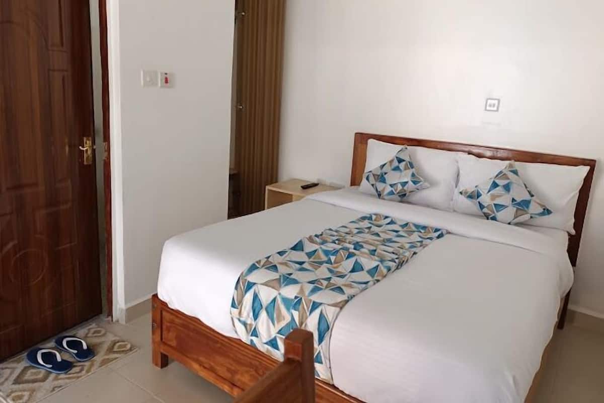 Una cama bien tendida con una colcha de estampado geométrico, un cabecero de madera y dos almohadas con un diseño similar.