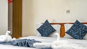 Un lit bien fait, avec deux oreillers, une tête de lit en bois et une porte visible au fond.