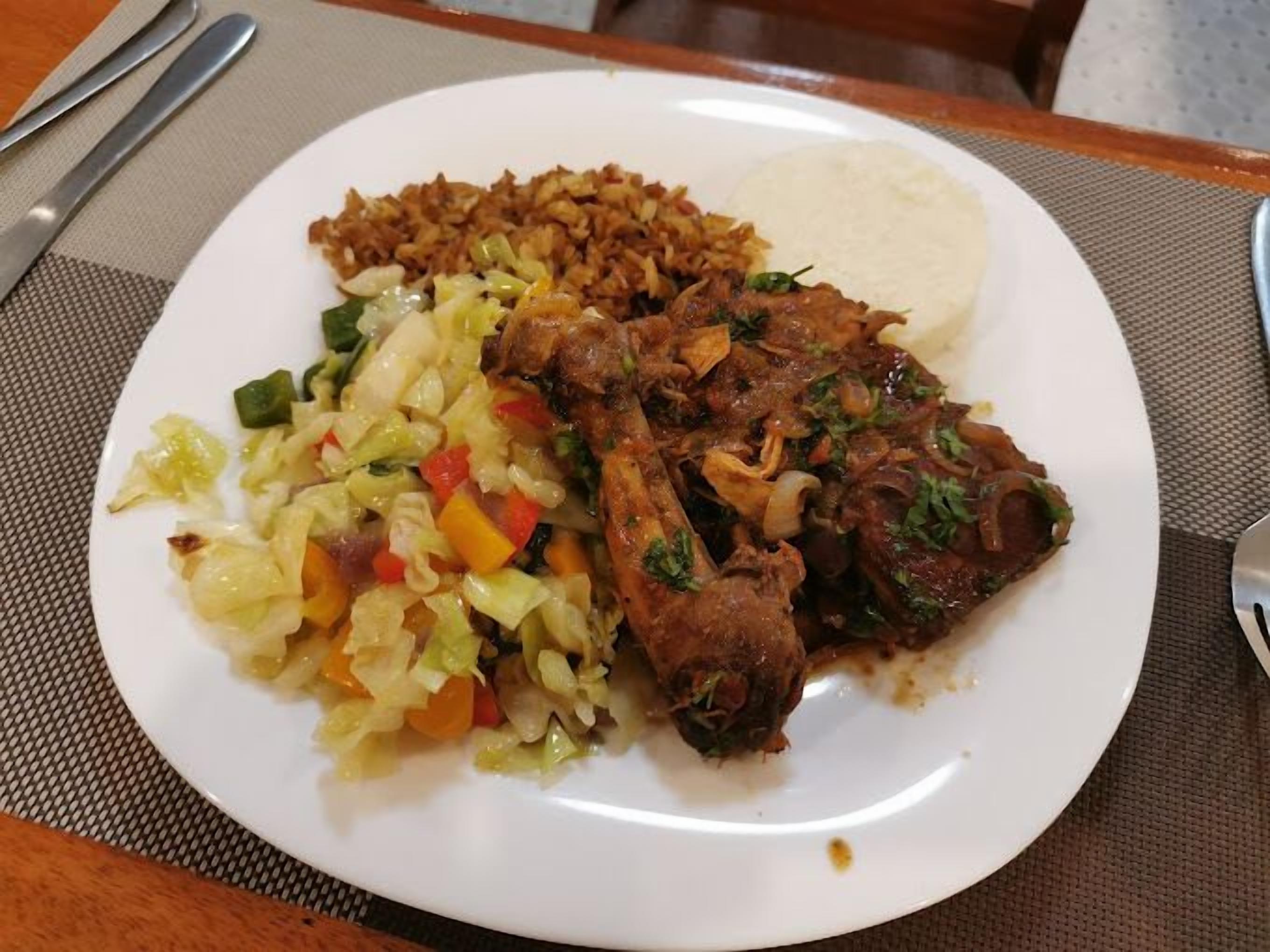 A plate with a meat dish, a side of rice, and a portion of cabbage.
