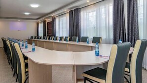 Une salle de conférence équipée d’une longue table, de chaises et d’un écran de projection.