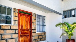 Un bâtiment avec une porte en bois, des murs en briques et un pot de fleurs.