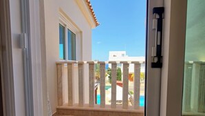 Un balcón con vista a una piscina y edificios al fondo.