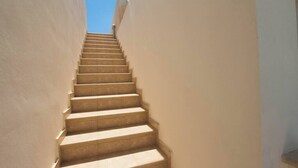 Una escalera que sube en un estrecho pasillo con paredes lisas.