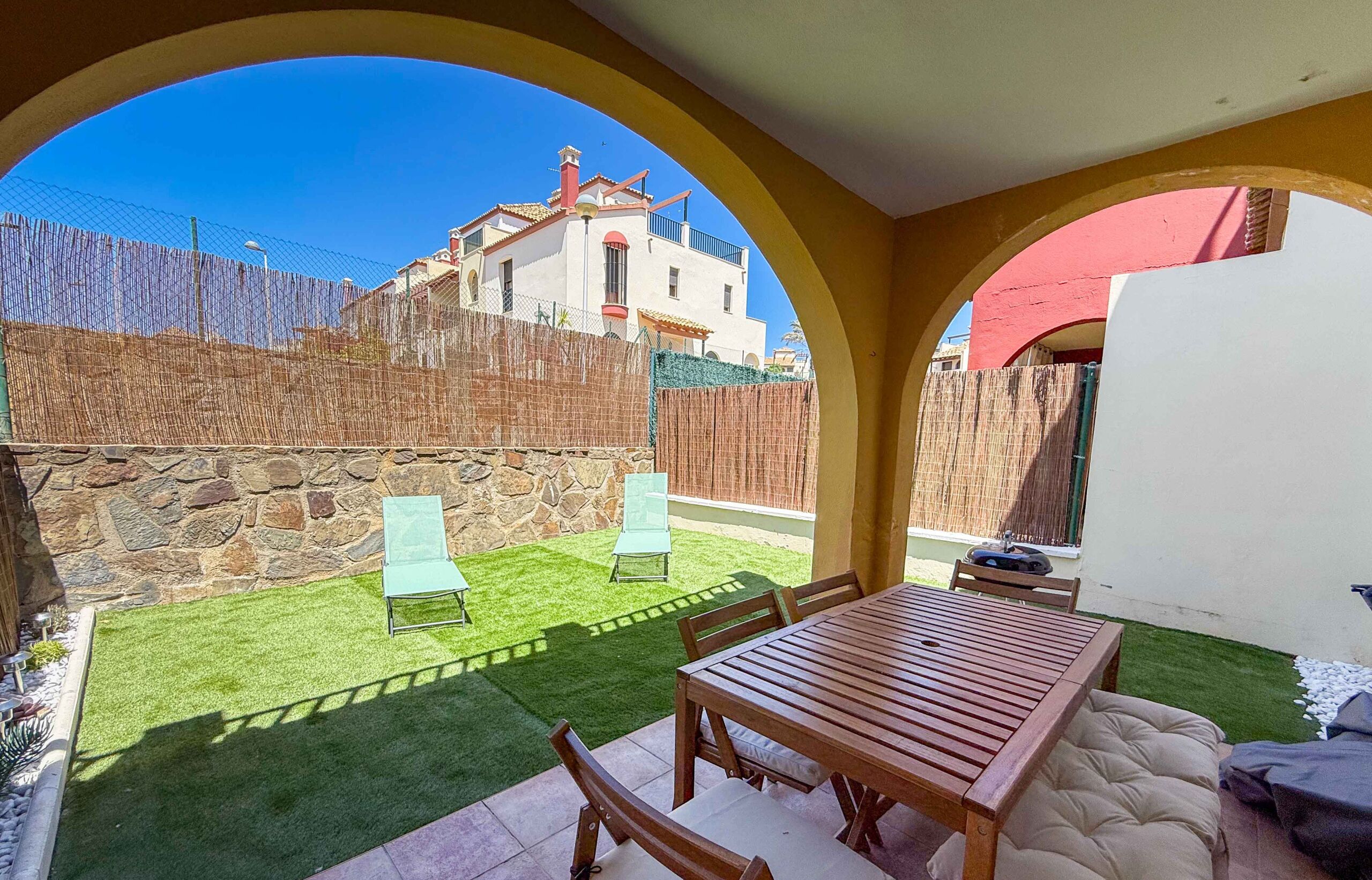 A patio area with a table and chairs, a small lawn, and a stone wall.