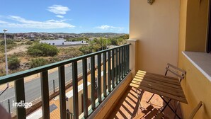 A balcony with a view of a residential area and a hill.
