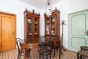 A dining area with a wooden table and chairs, a chandelier, and a green door.