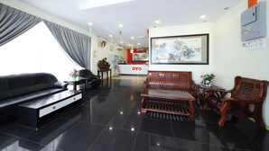 A modern living room with a black sofa, wooden furniture, a dining table, and a kitchen area in the background. - Hotel O Batu Ferringhi Beach formerly ESQ Ferringhi (George Town)