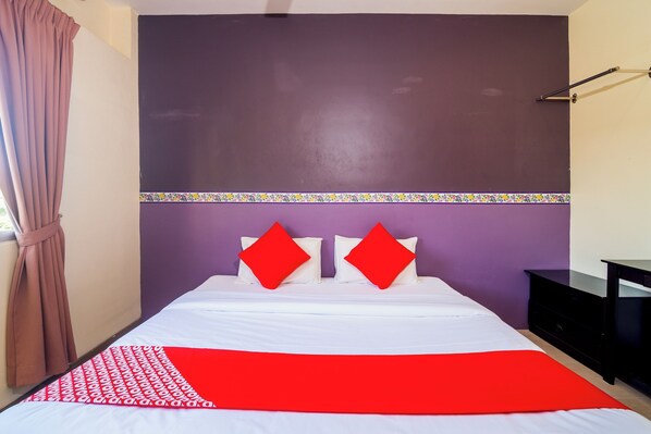 A bed with white and red bedding, a purple accent wall, and a black nightstand. - Hotel O Batu Ferringhi Beach formerly ESQ Ferringhi (George Town)