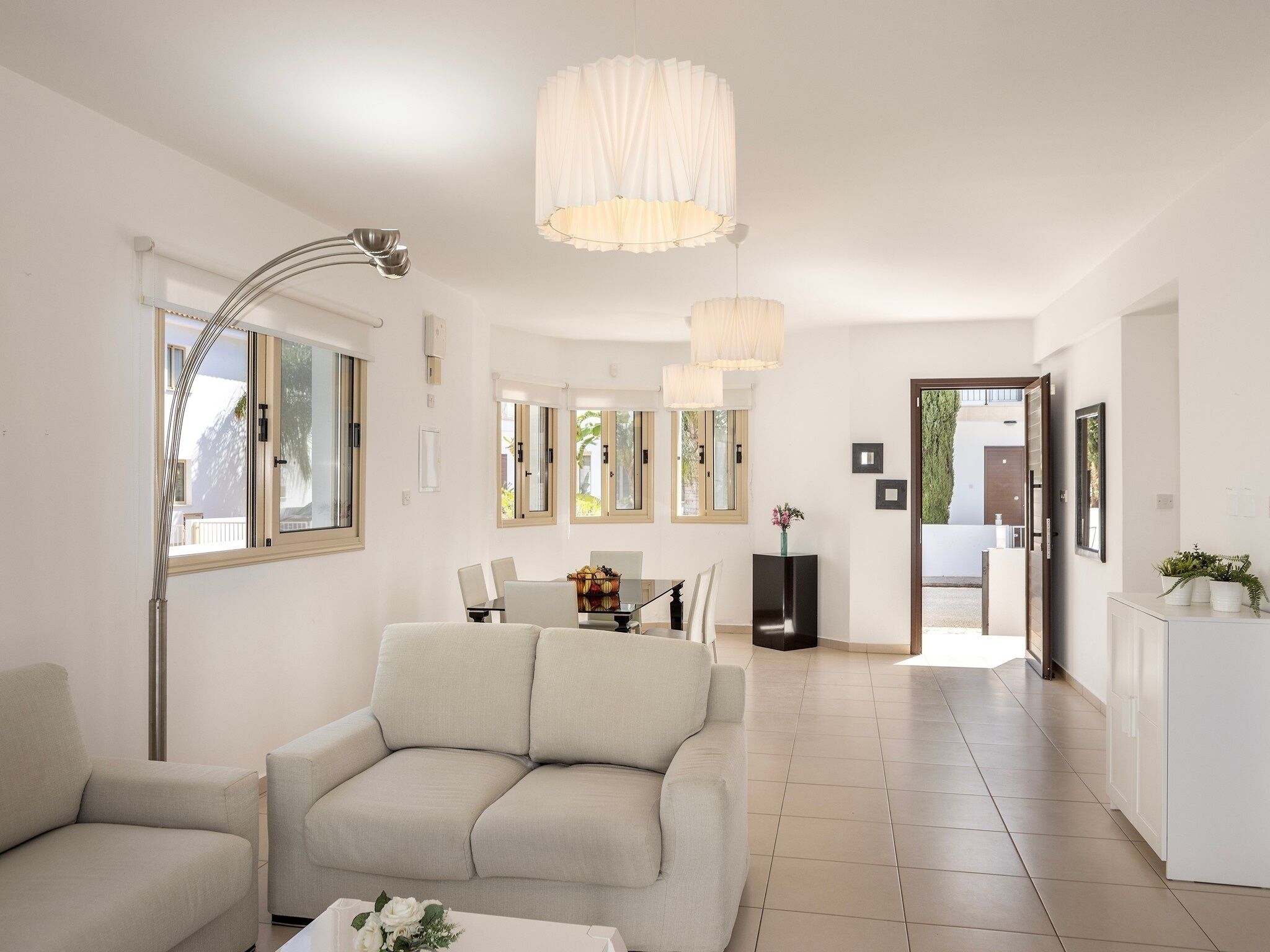 A modern living room with a sofa, a dining table, and a kitchen area.