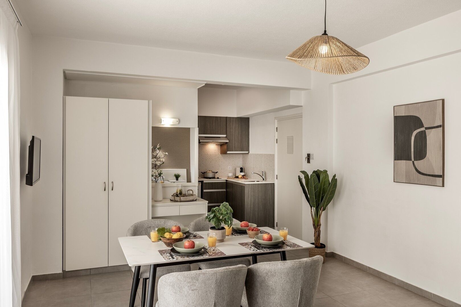 A modern kitchen with white cabinets, a dining table with chairs, and a hanging light fixture.
