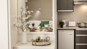 A modern kitchen with a white countertop, a small refrigerator, a stove, and a hanging light fixture. - Studio apartment in the heart of Protaras (Protaras)