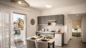 Une cuisine moderne avec des meubles gris, un plan de travail blanc et un coin repas équipé de deux chaises.