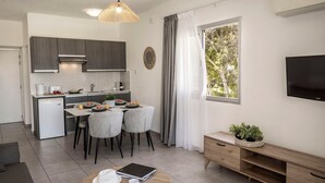 A modern kitchen with grey cabinets, a white refrigerator, and a dining table set for four. - 1 bedroom apartment in the heart of Protaras (Protaras)
