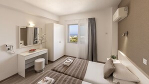 A modern hotel room with a large bed, a separate sofa, a vanity with a mirror, a hairdryer, and a view of the city. - 1 bedroom apartment in the heart of Protaras (Protaras)