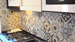 A kitchen with a gas stove, sink, and Bosch microwave.