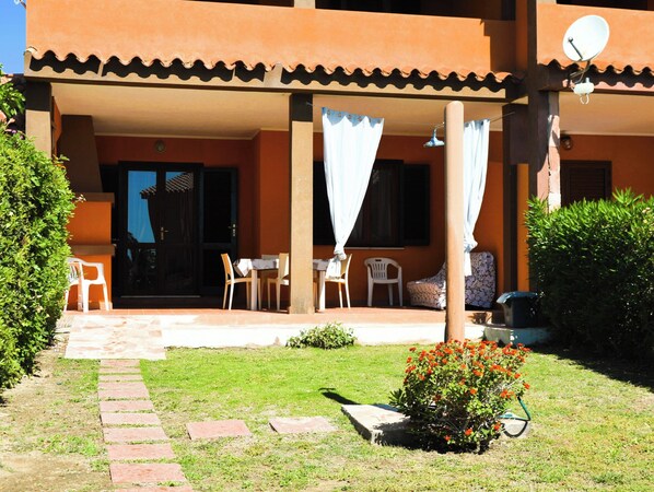A building with a covered patio area, outdoor seating, and a garden with a small flower bed. - AmareSardegna 1with Garden (Costa Rei)