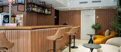 A bar area with a wooden bar counter, bar stools, and a seating area with a sofa and armchairs.