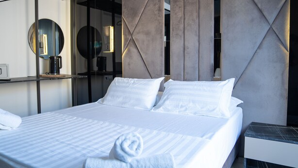 A modern hotel room with a neatly made bed, a bedside table, and a wall-mounted mirror. - MEFOLINKEL SUITS HOTEL (Lloret de Mar)