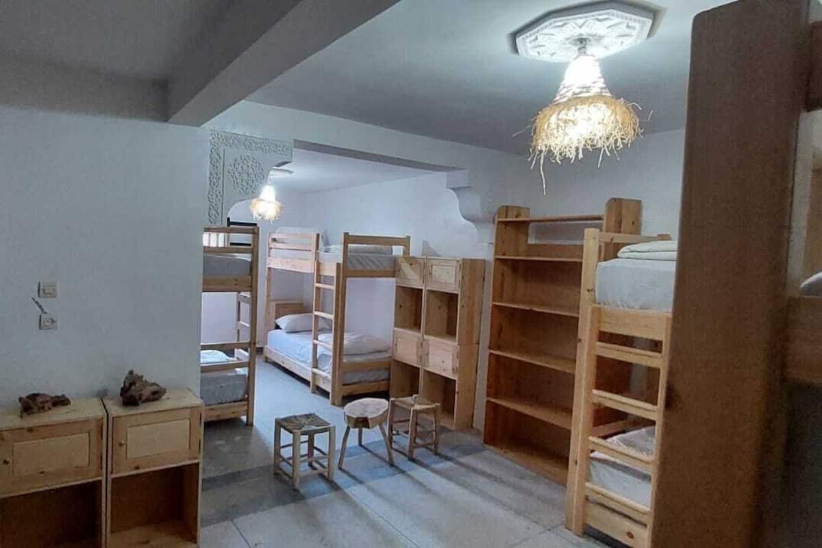 A dormitory room with bunk beds, a desk, and a chair.