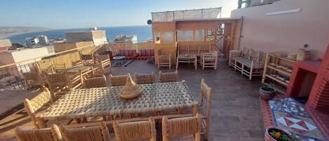 Une terrasse sur le toit, dotée de meubles en osier, d’un sol carrelé et offrant une vue sur la mer.