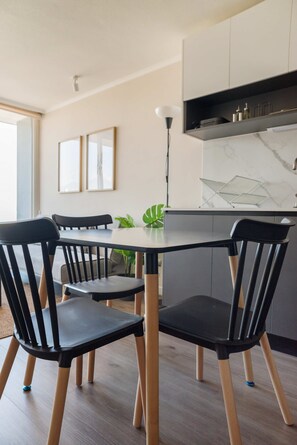 A modern kitchen with a marble countertop, black chairs, and a dining table. - Central Apartment with Balcony and Free Parking (Unknown)