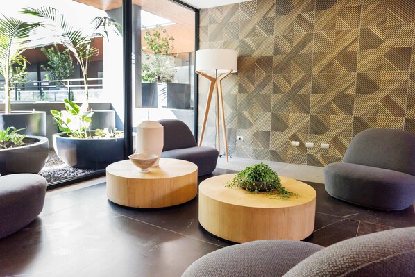 A modern living room with round wooden coffee tables, grey sofas, and a large floor lamp.