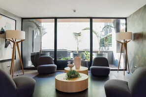 A modern living room with a large window, two grey armchairs, a round wooden coffee table, and two floor lamps. - Bright Apartment in Prime Nunoa: Gym and Balcony (Unknown)