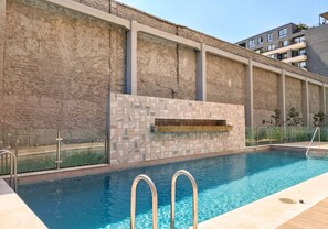 A swimming pool with a tiled wall and a metal ladder.