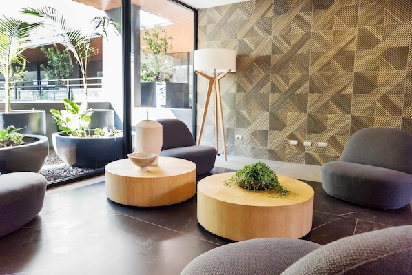 A modern living room with round wooden coffee tables, grey sofas, and a large floor lamp.