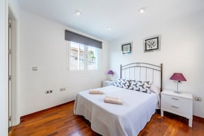 A bedroom with a bed, two bedside tables, a window, and a door.