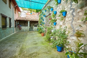 A courtyard with stone walls, potted plants, and a tiled floor.