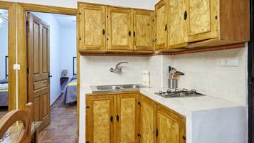 A kitchen with wooden cabinets, a sink, and a stove.