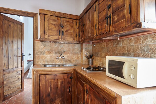 Cocina con armarios de madera, un lavamanos, una estufa y un microondas.