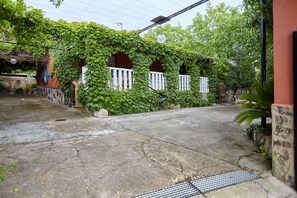 A courtyard with a stone pathway, a white fence, and a building partially covered by green vines.