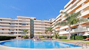 Un hôtel moderne doté d’une piscine, de nombreux balcons et offrant une vue sur un ciel d’un bleu éclatant.