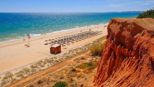 Une plage offrant une vue dégagée sur l’océan, une rive sablonneuse et une falaise rocheuse.