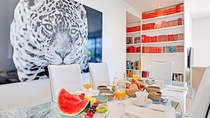 Un coin repas avec une table mise pour le petit-déjeuner, une bibliothèque remplie de livres et une grande image de tigre accrochée au mur.