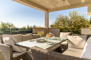 An outdoor seating area with wicker furniture, a glass table, and a view of trees and sky. - Villa Bura Zadarvillas (Stankovci)