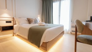 Ein modernes Schlafzimmer mit einem hölzernen Bett, einem Nachttisch, einem Sessel und einem großen Fenster mit Vorhängen.