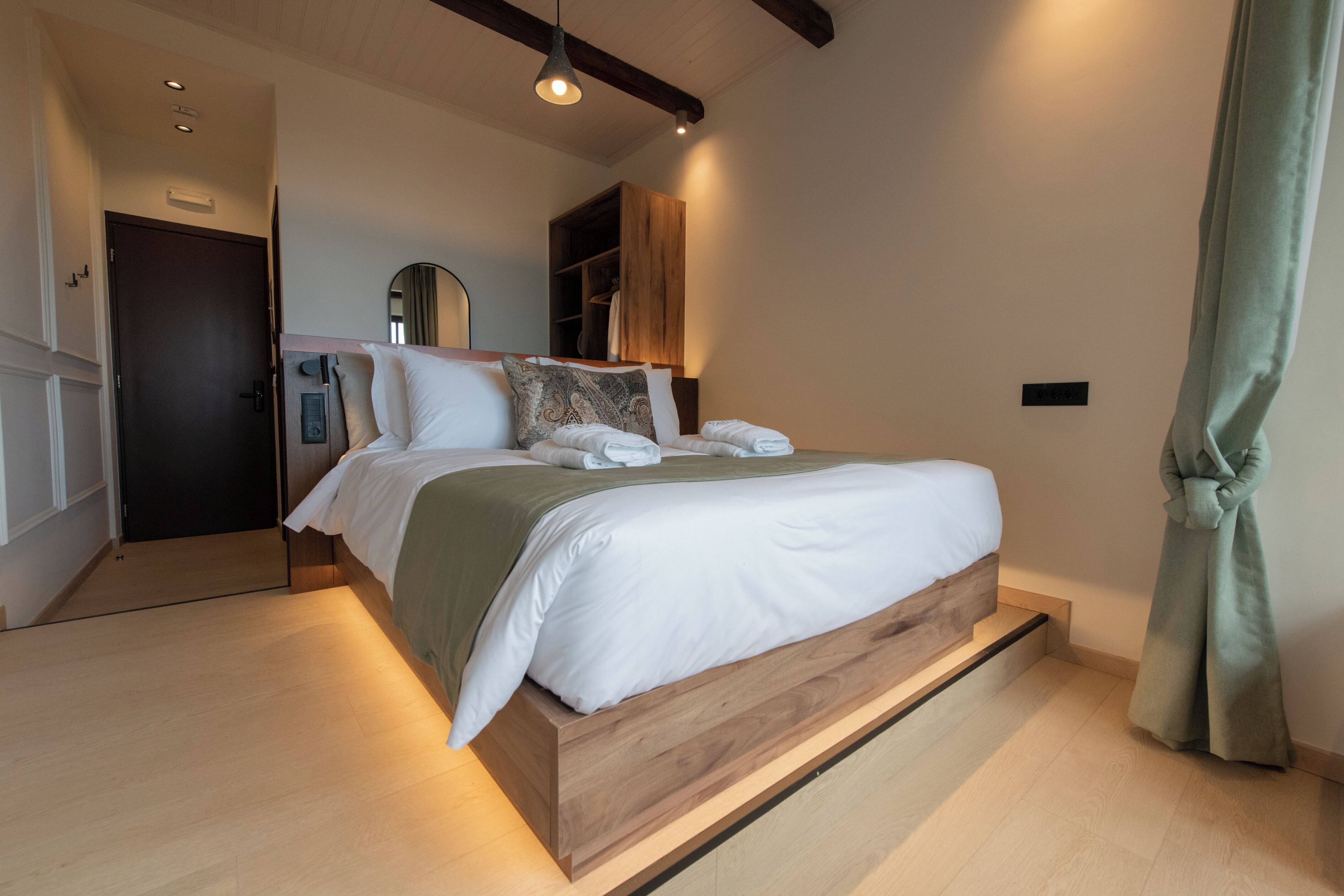 Ein modernes Schlafzimmer mit einem Holzbettgestell, einem Einbauschrank und einem großen Spiegel.