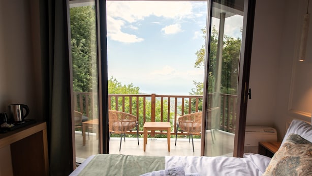 Ein Schlafzimmer mit Bett, Schreibtisch und einem Balkon mit Stühlen und Tisch.