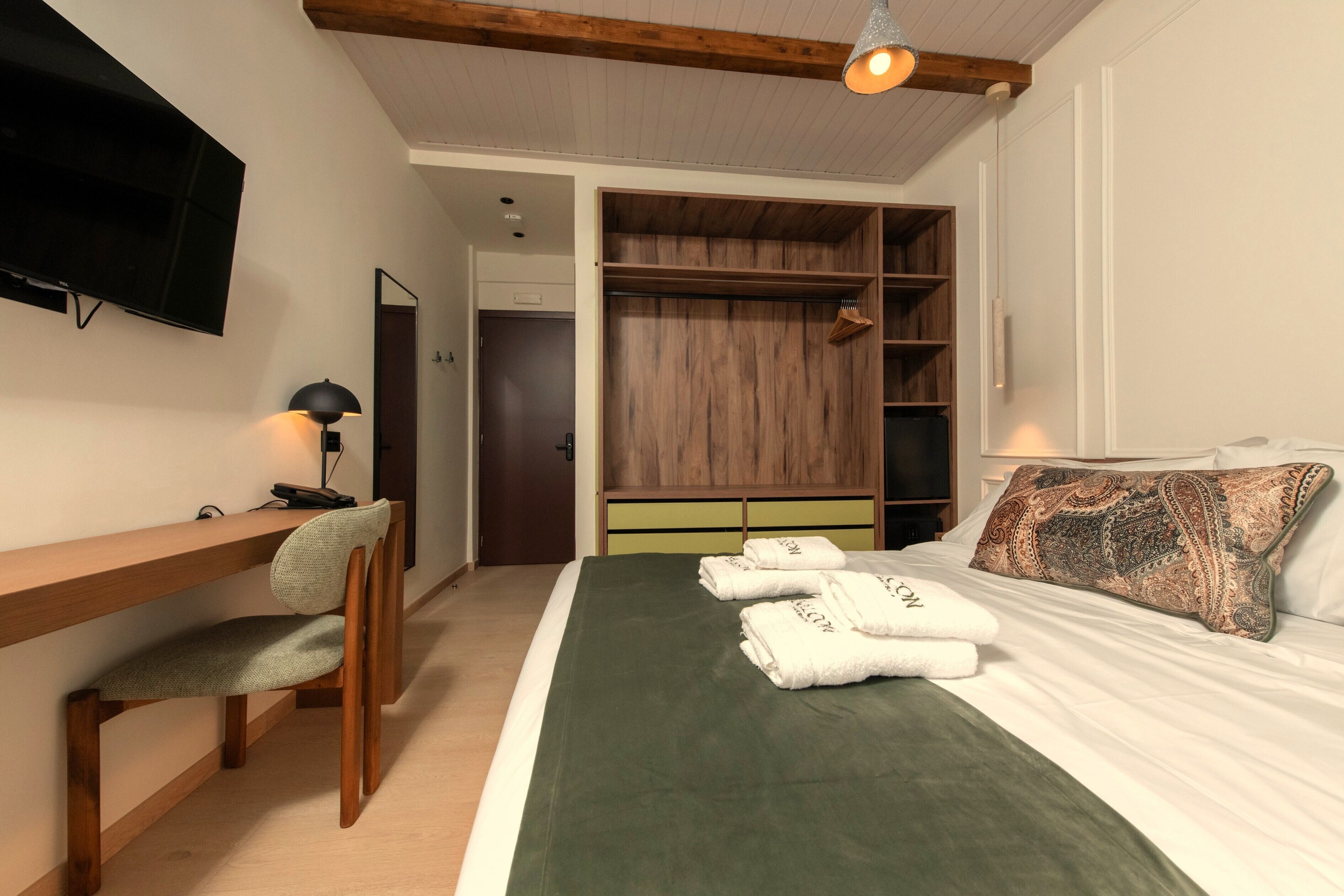 Une chambre à coucher avec un lit, un bureau, une chaise, une télévision et une armoire.